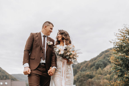 The bride in her wedding dress looks lovingly at the groom. Wedding trip in the mountainsの写真素材