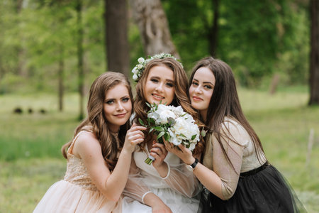 Wedding walk in the forest. Brides and their friends pose against the background of the forest. A large group of people are having fun at their friends' weddingの写真素材