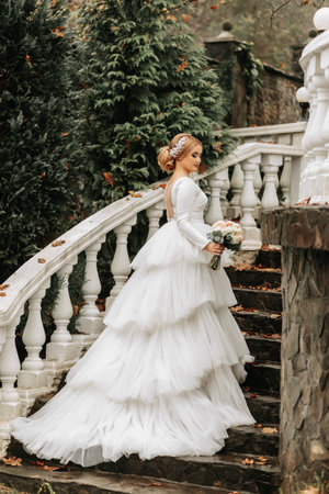 Portrait of a bride in a wedding dress with a train on elegant steps. Full length photo. Wedding in a top locationの写真素材