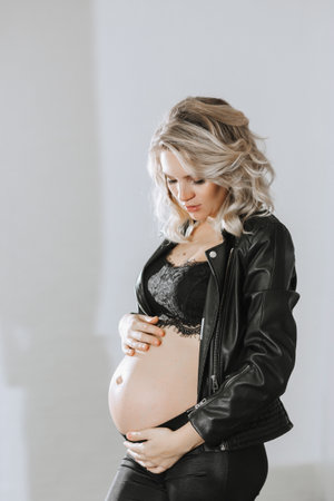 studio stylish portrait of a beautiful pregnant young woman in a black suitの写真素材