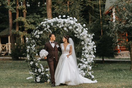 Happy bride and groom after wedding ceremony. round ceremonial arch. Long white dress of the brideの写真素材