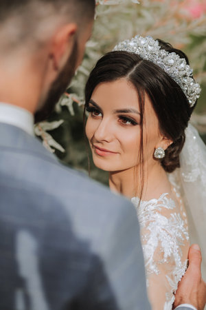 the bride in a beautiful white dress with sleeves and a crown on her head and a bouquet of hydrangeas in her handsの写真素材