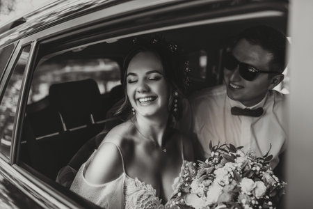 young happy bride and groom are rejoicing after the wedding ceremony in their carの写真素材