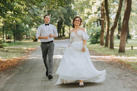 A wedding couple, a happy bride and groom are running in the park to the place of the wedding ceremony. Wedding conceptの写真素材