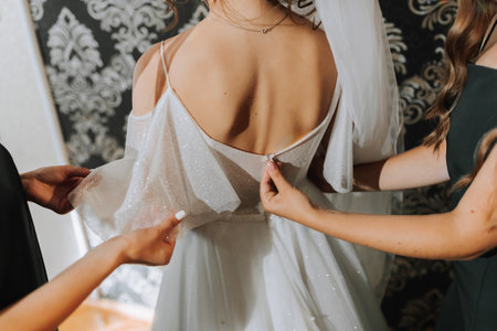 girlfriends help the bride with her dress. Close-up photo. Girlfriends help the bride.の写真素材