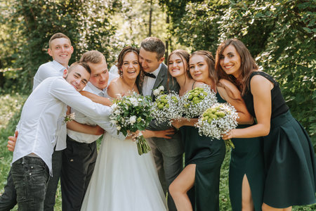The bride and groom celebrate their wedding with friends outdoors after the ceremonyの写真素材