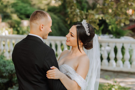 portrait of a young beautiful wedding couple in the garden, the bride in an off-the-shoulder wedding...