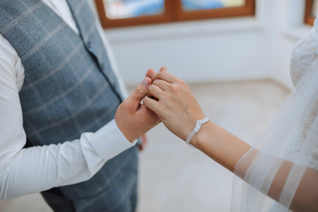 cropped portrait of bride and groom holding hands. A beautiful young bride in a wedding dress, the groom in a classic suit. Free spaceの写真素材