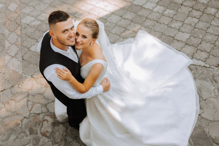 young beautiful wedding couple romantically hugging and looking at the camera, photo taken from aboveの写真素材