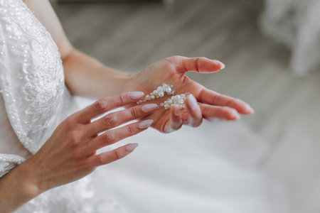 women's pearl earrings in the hand of the bride, handmade, close-upの写真素材