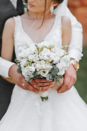 wedding bouquet in the hands of the bride and groom. Emphasis on the wedding bouquet, the bride is out of focusの写真素材