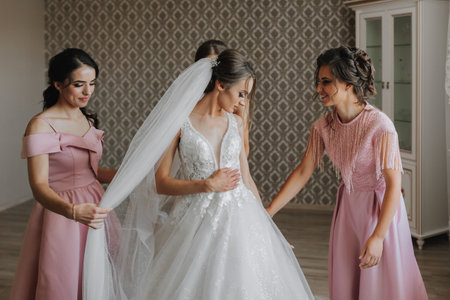 the bride, with her girlfriends in matching pink dresses, in the morning, help the bride get ready for the wedding ceremonyの写真素材
