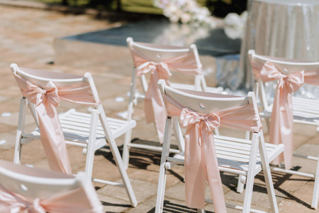 Wedding ceremony in the yard. Round arch made of flowers and many white chairs with pink ribbons. Wedding theme. Holiday conceptの写真素材
