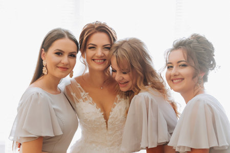 Portrait of the bride with her friends. The bride in a voluminous white dress and her beautiful friends in white evening dresses are posing. Brunettes. Open shoulders. Morning of the bride.の写真素材