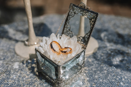Wedding rings in a glass box, on a white flower. Wedding details. Holiday conceptの写真素材