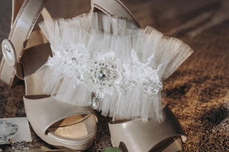 Beige open elegant shoes. The bride's headband sits between a pair of beige sandals. The bandage on the bride's leg is on the shoes, pointedly. Fashion. Style. Wedding photoの写真素材
