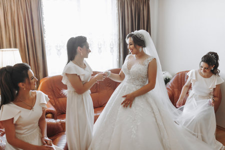 Wedding theme. A friend puts a bracelet on the bride. Four brunettes. The last minutes of preparations for the wedding. The same outfitの写真素材