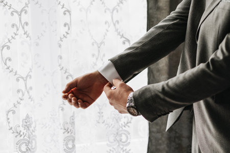 Male portrait. Photo session by the window. Groom's collection. The groom puts on a jacket. Wedding...