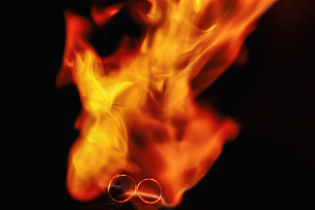 two wedding rings in the flames of fire. Wedding. Traditions. Fiery flame on a dark background