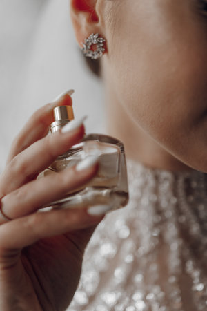 The bride holds perfume. focus on perfume. Beautiful hands and manicure