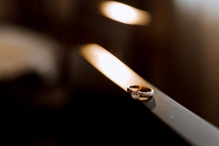 Gold wedding ring with a diamond on a brown background, focus on the wedding ring. blurred...