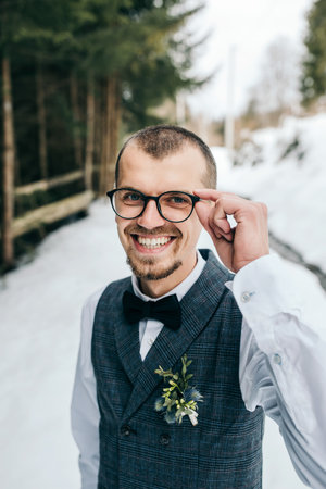 Wedding portrait of the groom. The groom stands against the background of the winter forest. A man...