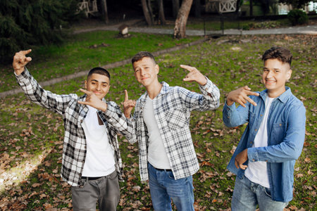 Three teenage boys, posing in nature, rejoicing, running and having fun. Teenage classmates are resting against the background of an autumn forest.の写真素材