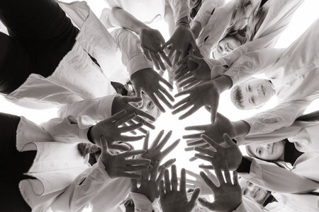 A large group of smiling young people standing, hugging, looking at the camera and stretching their arms down. Group of cheerful teenage people in a circle looking down. Low viewing angle. Copy space.の写真素材