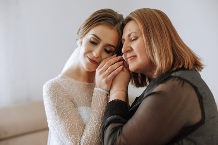 A beautiful and happy mother and her daughter, the bride, are standing next to each other. The best...