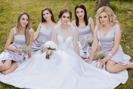 Group portrait of the bride and bridesmaids. A bride in a wedding dress and bridesmaids in silver dresses hold stylish bouquets on their wedding day.の写真素材