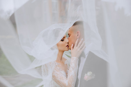 Wedding. Love and couple in garden for wedding. Celebration of ceremony and commitment. Save the date. Trust. The bride and groom embrace. The groom embraces the bride under the veil.の写真素材