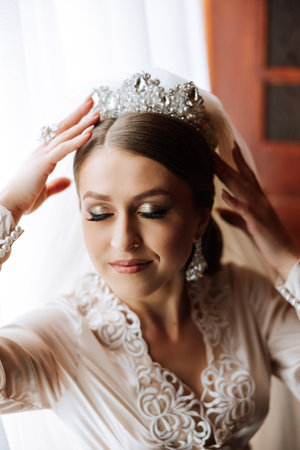 Beautiful bride in a dressing gown in the morning before the wedding ceremony. Incredible hairstyle of the bride. Natural and modern makeup. Portrait of a young bride in a dressing gown.の写真素材