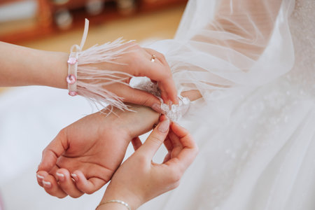 Morning of the bride. The bride's maid of honor helps the bride lace up her dress, fasten buttons on the dress or sleeves. Girlfriends help the bride fasten her dressの写真素材