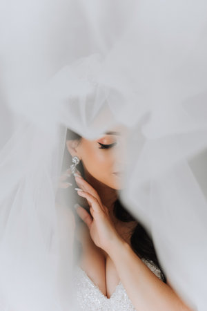 Portrait of the bride in the hotel room. A beautiful young girl is dressed in a white wedding dress. Modern wedding hairstyle. Natural makeup.の写真素材