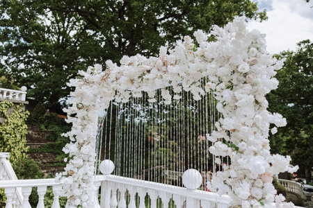 The groom is crying during the wedding ceremony, the bride is holding a bouquet and looking at him, near the flower arch. Summer wedding in natureの写真素材