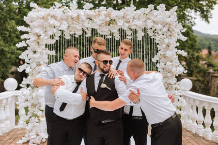 Cheerful, young, energetic witnesses of the groom next to the groom. Friends congratulate the groom....