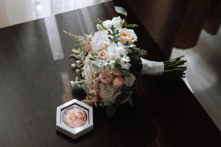 On the floor are men's dark leather shoes and a black belt, a man's suit on a mannequin, a wedding bouquet of flowers, wedding rings, men's perfume. Photo, top view.の写真素材