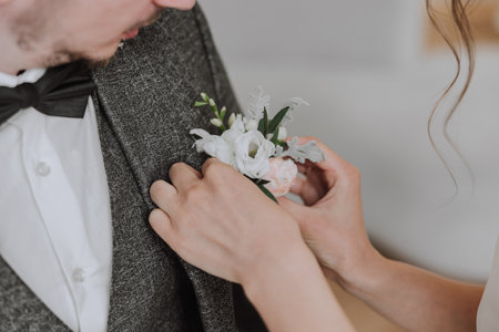 The bride chips the boutonniere to the groom. Cropped photo. Details at the wedding. High quality photo.の写真素材