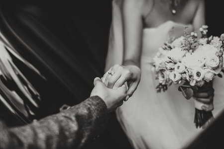 Groom helps happy young bride to get out of wedding car. black and white photoの写真素材