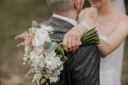 The bride and groom embrace. The bride gently hugs the groom by the shoulders. Beautiful wedding couple. The concept of romance in a newlyweds relationship. Honeymoon.の写真素材