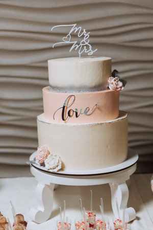 a three-tiered wedding cake decorated with flowers stands on a decorative stand. Decorative wedding cake. Beauty is in the details.の写真素材