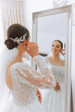 Portrait of the bride in the hotel room. A beautiful young girl is dressed in a white wedding dress. Modern wedding hairstyle. Natural makeup.の写真素材