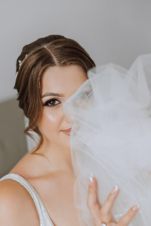 Portrait of the bride in the hotel room. A beautiful young girl is dressed in a white wedding dress. Modern wedding hairstyle. Natural makeup.の写真素材