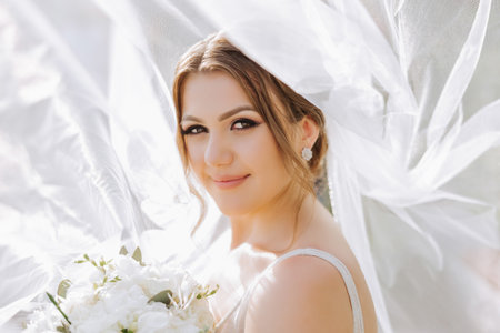 Beautiful bride with wedding flowers bouquet, attractive woman in wedding dress. Happy newlywed woman. Bride with wedding makeup and hairstyle. Smiling bride. Wedding day. Gorgeous bride. Marriage.の写真素材