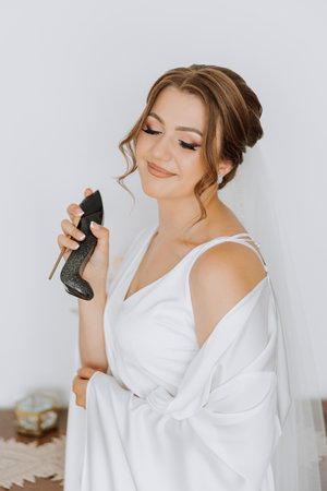 A beautiful young bride girl holds an elegant bottle of perfume in her hand and is ready to spray herself. Morning of the bride before the wedding ceremony.の写真素材