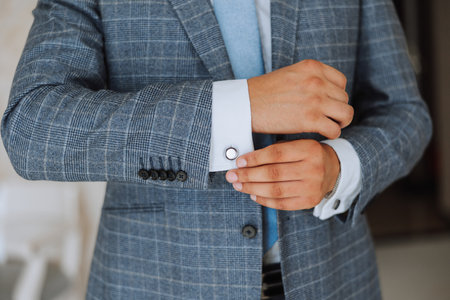 Hands button up the buttons on his shirt. The process of fastening the buttons on his white shirt....