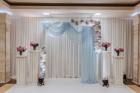 The photo zone at a wedding or birthday celebration is decorated with flowers and illuminated by artificial lightの写真素材