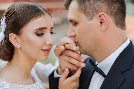 Wedding kiss. Groom kisses bride's hand. Weddng love. Close-up of a young man kissing his wife's hand with gold ring while making a marriage proposal.の写真素材