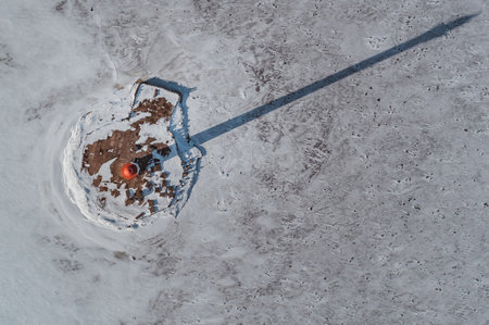The lighthouse is in winter on the river bank. View from above.