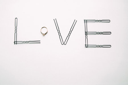 The word love is made of hairpins and an engagement ring.の写真素材
